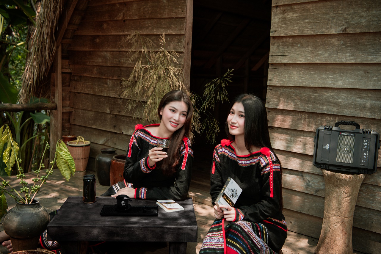 Description: Two women in black and red dresses sitting at a table outside a houseDescription automatically generated